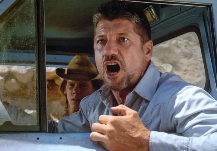 Fred Ward, attore noto per film d'azione, con espressione angosciata in auto. La sua causa morte è stata una malattia.
