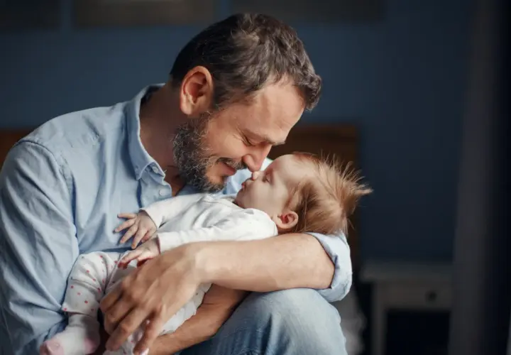 Szczęśliwy ojciec tuli swoje dziecko, ciesząc się urlopem ojcowskim.