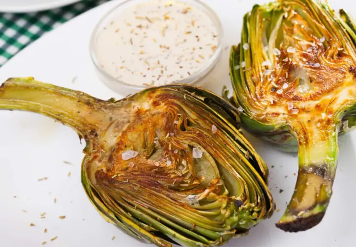 Alcachofas gratinadas con queso, tiernas y doradas, listas para disfrutar con una cremosa salsa.
