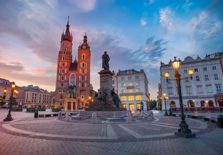 Kraków na weekend: Rynek Główny o zmierzchu z Kościołem Mariackim i pomnikiem Mickiewicza. Idealne miejsce na spacer.