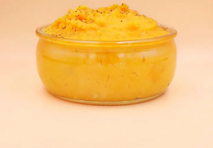 Pyszne, kremowe puree z batata w szklanym naczyniu, posypane świeżo mielonym pieprzem. Idealne jako dodatek do obiadu.