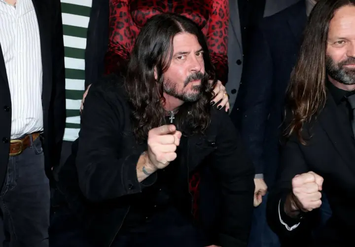 Dave Grohl z zespołu Foo Fighters wskazuje palcem, otoczony przez członków grupy.