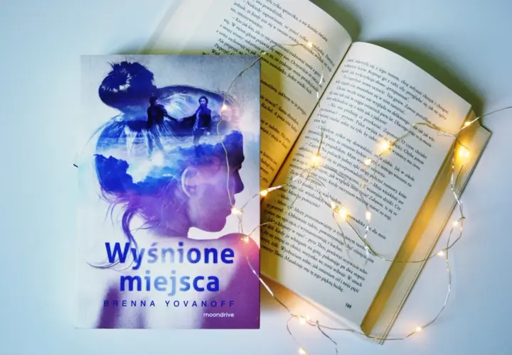 Osoba na okładce książki "Wyśnione miejsca" Brenny Yovanoff, otoczona magicznymi światełkami.