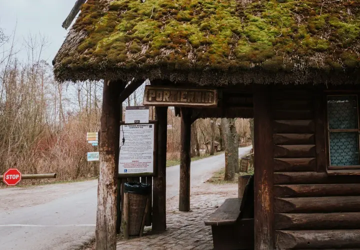 Drewniana portiernia z zielonym, mchowym dachem, zapraszająca do odkrywania atrakcji Biskupina.