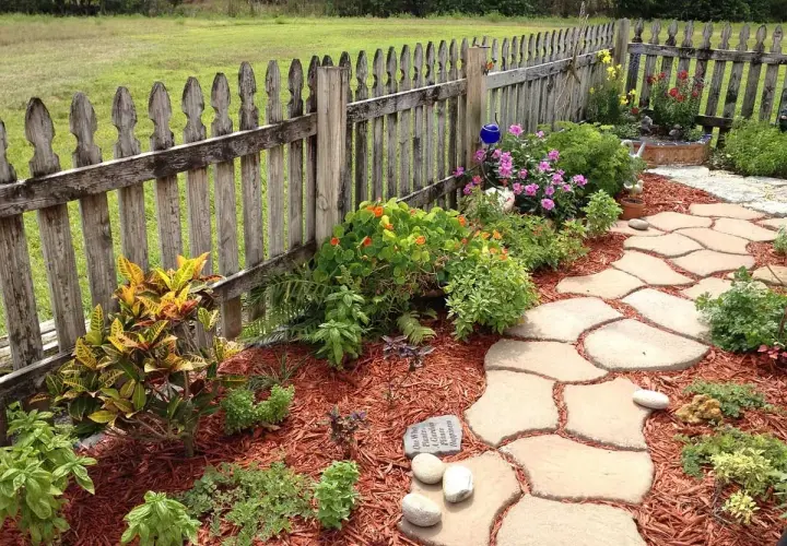 Ein geschwungener Steinweg führt durch einen blühenden Garten. Perfekt, um einen neuen Gartenweg anzulegen.