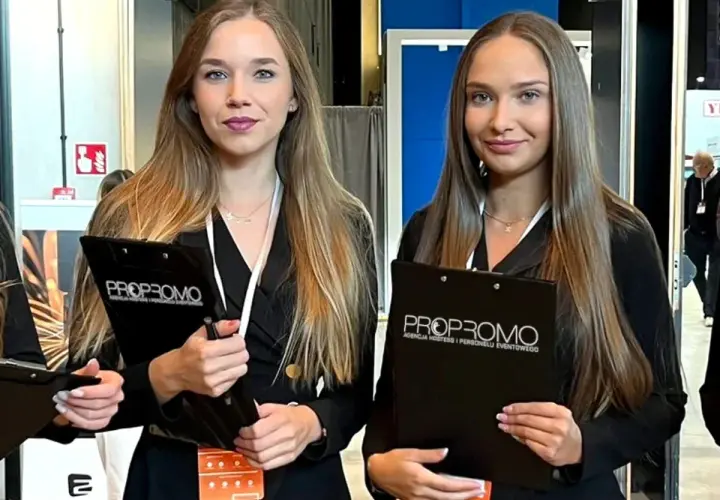 Dwie uśmiechnięte hostessa z agencji PROPROMO trzymają teczki z logo firmy.