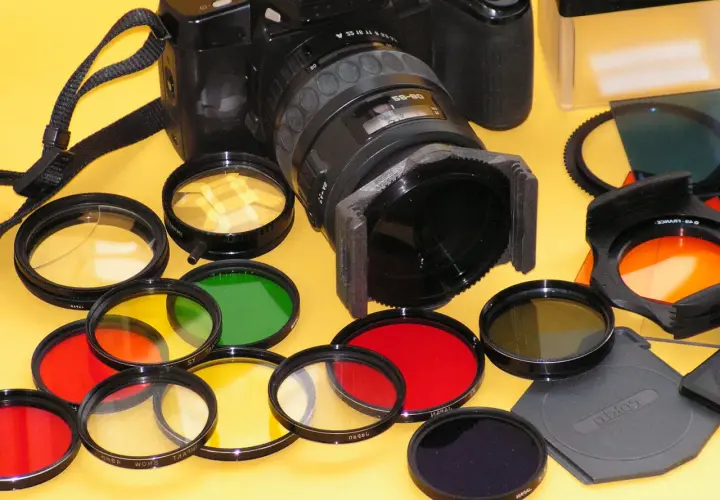 Una macchina fotografica con una varietà di filtri colorati (rossi, gialli, verdi, arancioni, blu) pronti per essere utilizzati per effetti creativi.