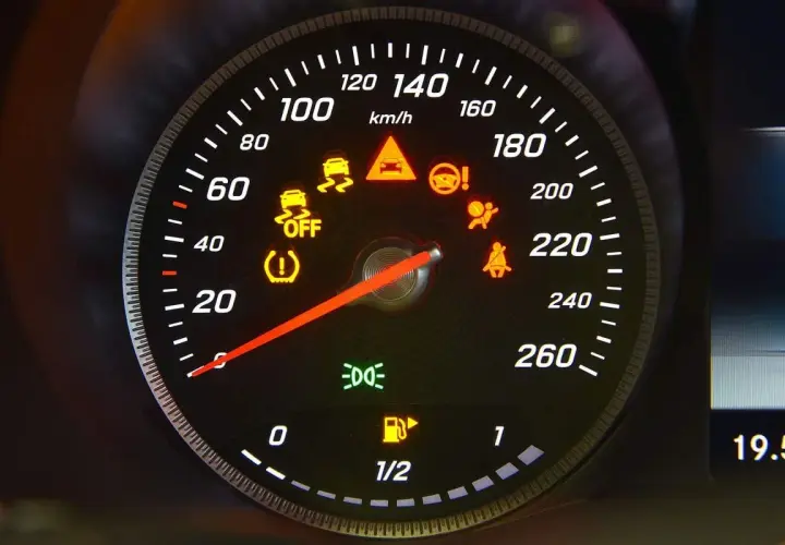 Cruscotto auto con varie luci della macchina spie accese: controllo stabilità, airbag, cinture, pressione pneumatici, carburante e fari.