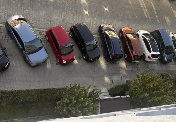 Szary samochód, czerwony, czarny, granatowy, rudy, biały, ciemnogranatowy i srebrny stoją na parkingu. Może to być inspiracja do wypełnienia wniosku o miejsce parkingowe wzór.