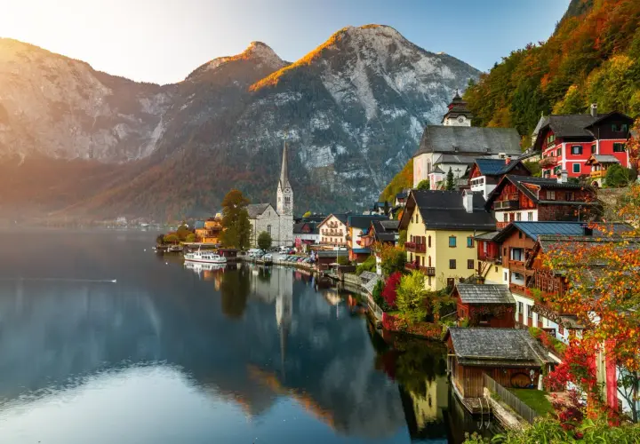 Hallstatt, Austria, un pueblo alpino con casas coloridas y una iglesia, reflejado en un lago sereno. Un ejemplo de los países más bonitos de Europa.
