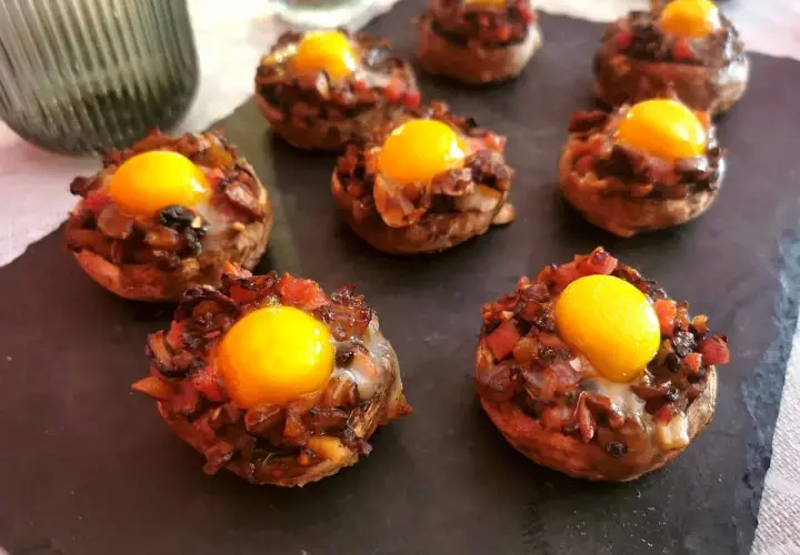 Champiñones rellenos con huevo y trocitos de tomate y cebolla, listos para disfrutar.