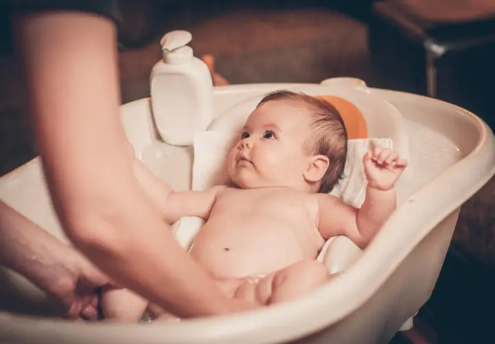 Malutkie dziecko w wanience, rodzic delikatnie myje jego nóżki. Kąpiel to ważny rytuał, od kiedy kąpać dziecko codziennie? Od pierwszych dni życia!