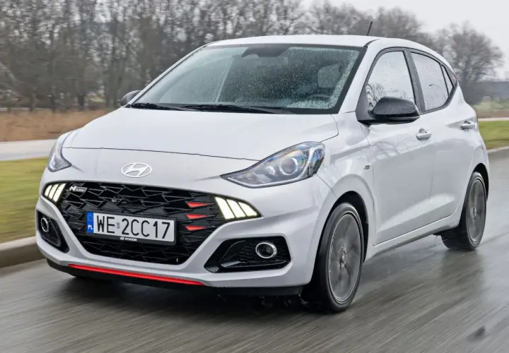 Biały Hyundai i10 N Line w ruchu, z widocznym grillem i światłami. Sprawdź aktualną hyundai i10 cena.