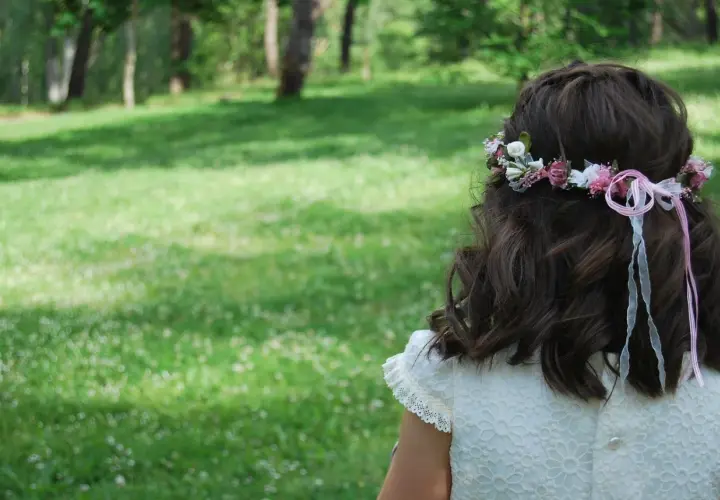 Niña con corona de flores y listones rosas, un ejemplo de peinados para niñas fáciles y bonitos.