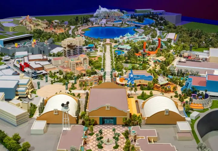 Maquette détaillée d'un parc d'attractions Disney avec lac, montagnes, bâtiments et attractions.