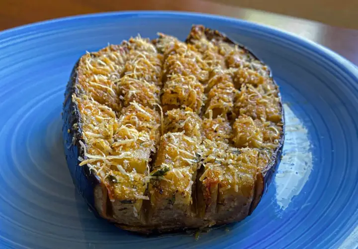 Melanzane a barchetta ripiene e gratinate, pronte per essere gustate su un piatto blu.