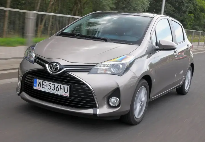 Szary Toyota Yaris w ruchu drogowym, widok z przodu.