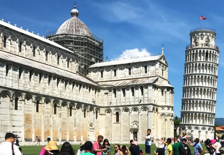 Turyści podziwiają, gdzie jest krzywa wieża w Pizie, obok katedry i baptysterium na Piazza dei Miracoli.
