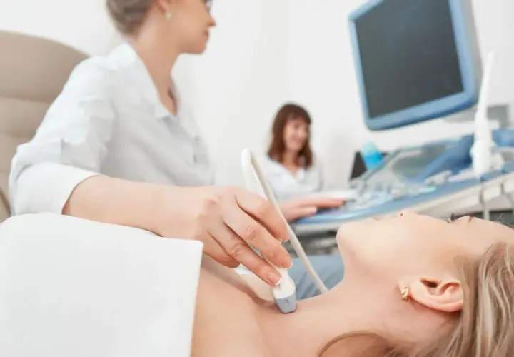 Ecografia tiroidea: un medico valuta la salute della paziente, un'indagine che può influenzare quanto guadagna un endocrinologo.