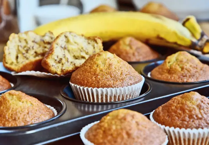 Muffin alla banana appena sfornati nella friggitrice ad aria, con una banana matura sullo sfondo.