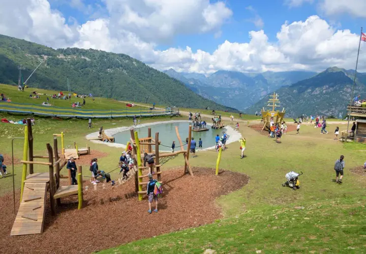 Un'area giochi con un laghetto e un galeone, dove tante famiglie si divertono in montagna con i bambini.