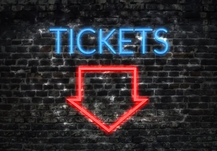 Napis "TICKETS" świeci na niebiesko nad czerwoną strzałką wskazującą w dół. To znak, jak kupić bilet online.