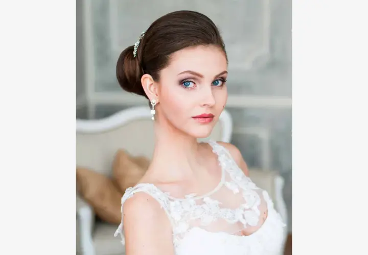 Panna młoda z eleganckim upięciem i biżuterią, w białej sukni.