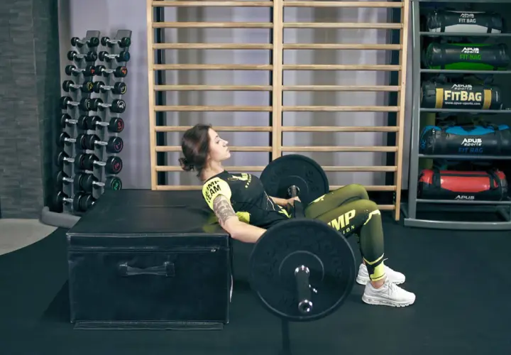 Kobieta wykonuje hip thrust, ćwiczenie angażujące mięśnie pośladków i ud.