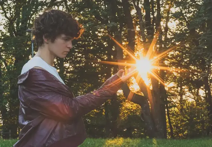 Chłopak w skórzanej kurtce łapie promienie zachodzącego słońca. Ciekawe fotografie z magicznym blaskiem.
