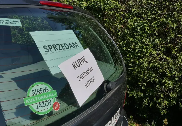 Tylna szyba samochodu z naklejkami "SPRZEDAM", "KUPIĘ ZADZWOŃ JUTRO!" i "STREFA KULTURALNEJ JAZDY".