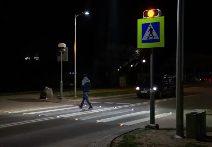 Nocą pieszy przechodzi przez pasy, oświetlone odblaskami. Obok miga żółte światło sygnalizatora, a znak d6 przypomina o obowiązku ustąpienia pierwszeństwa.