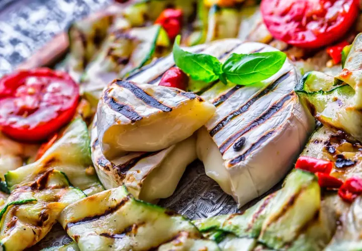 Co na grilla oprócz mięsa? Grillowany ser camembert z cukinią i pomidorami, udekorowany bazylią.