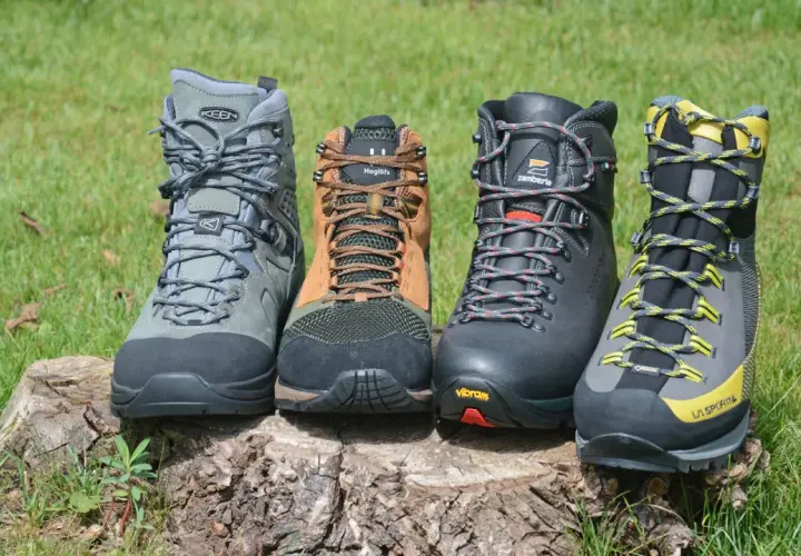 Four hiking boots, showcasing what boots are made of, sit on a log. Materials include leather, mesh, and rubber soles.