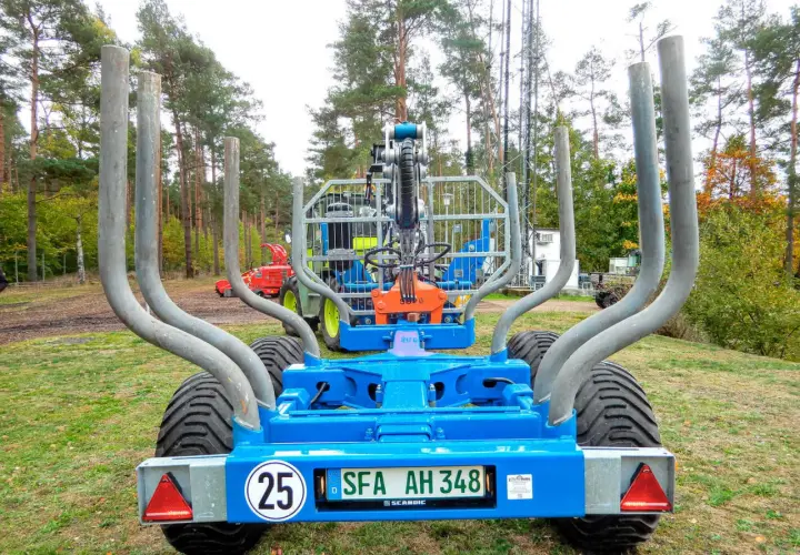 Ein blauer Rückewagen mit dem Kennzeichen SFA AH 348, bereit für den Einsatz im Wald. Dieses Folgekennzeichen landwirtschaft zeigt, dass er für den Transport von Holz bestimmt ist.