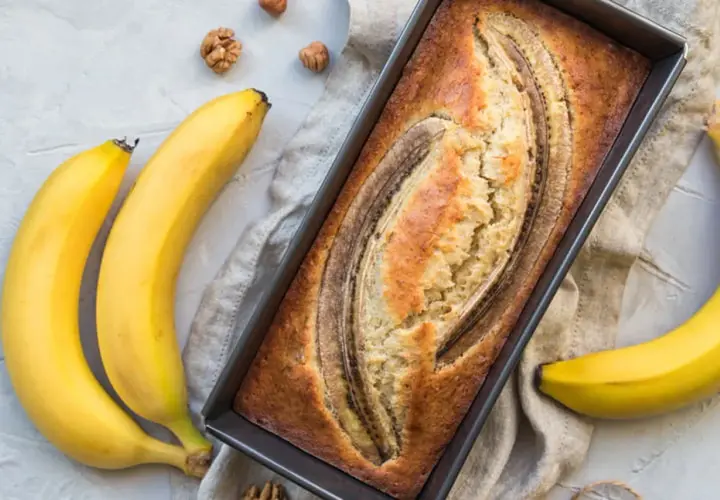Gâteau moelleux à la banane trop mûre, cuit à la poêle, avec des bananes fraîches et des noix autour.