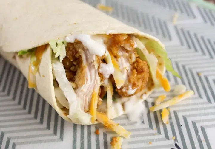 Klasyczny mcwrap z chrupiącym kurczakiem, serem i warzywami, polany sosem. Idealny na szybki posiłek, choć warto pamiętać o jego kcal.