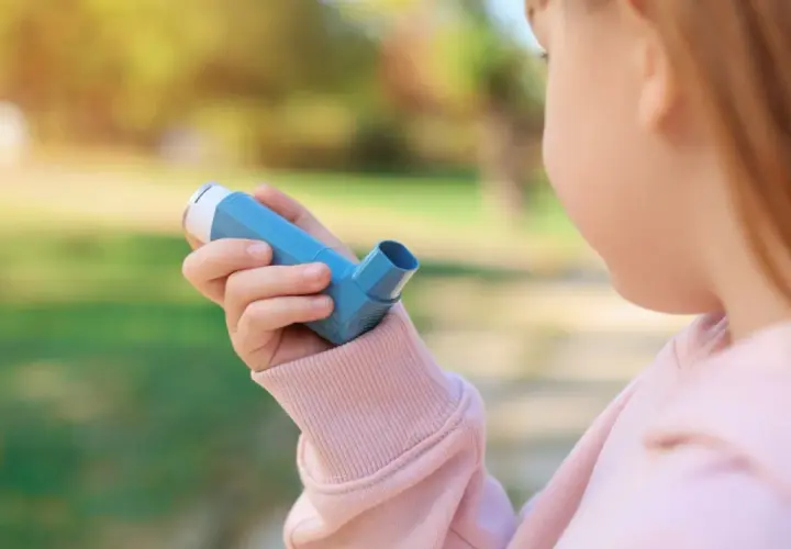 Bambina con inalatore blu, per gestire la tosse asmatica e i suoi sintomi.