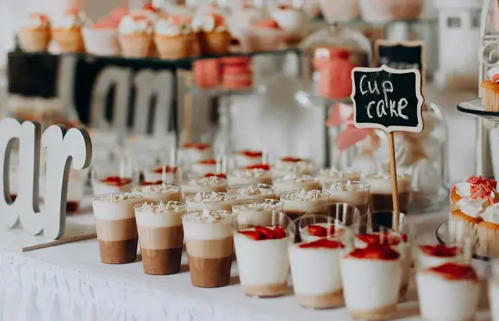 Un buffet de desserts festif, parfait pour une idée repas mariage été, avec des cupcakes, verrines et macarons.