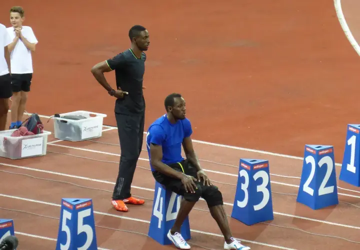 Usain Bolt, siedzący i stojący na bieżni, przypomina o jego rekordowej prędkości, która osiągnęła ponad 44 km/h.