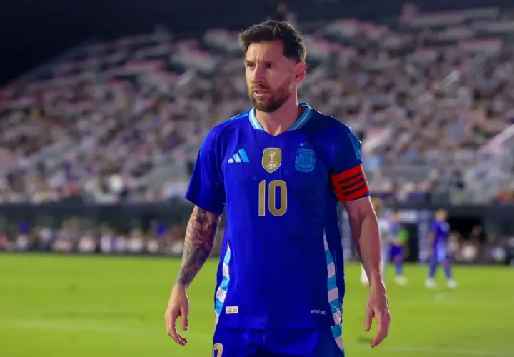 Messi w niebieskiej koszulce reprezentacji Argentyny, z numerem 10 na piersi, na tle trybun pełnych kibiców.