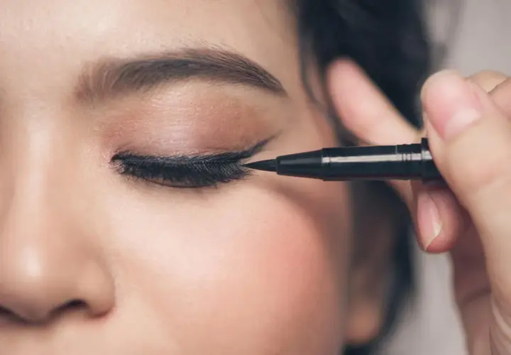 Precyzyjne malowanie odwrócone kocie oko makijaż. Czarny eyeliner podkreśla spojrzenie.