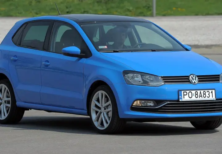 Niebieski VW Polo 2010 z czarnym dachem, zaparkowany na zewnątrz.
