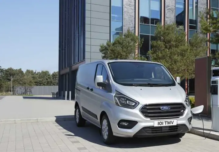 Furgoneta Ford Transit plateada cargando, con un edificio moderno al fondo. La presión de los neumáticos es clave para su eficiencia.