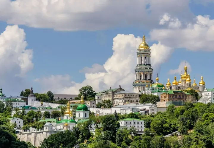 Kijów, z czego słynie Ukraina: złote kopuły cerkwi i majestatyczna dzwonnica Ławry Peczerskiej na tle błękitnego nieba.