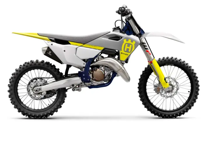 Motocykl crossowy Husqvarna TC125 w kolorze białym z żółtymi i niebieskimi akcentami, gotowy do wyścigów.