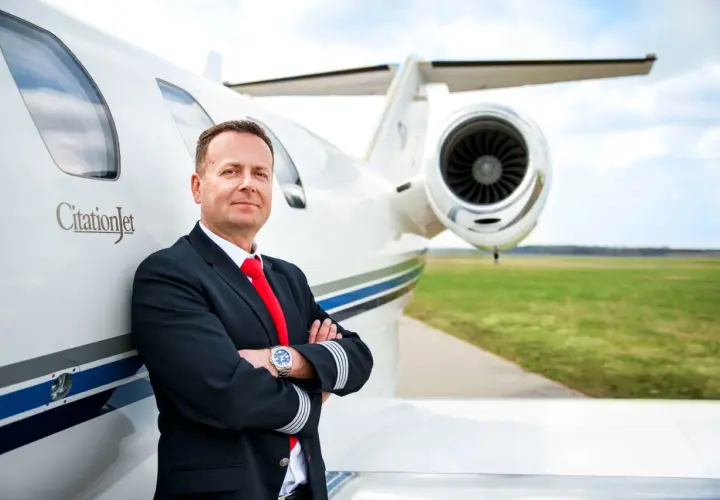 Pilot w mundurze przy CitationJet. Marzysz, jak zostać pilotem samolotu pasażerskiego? To zdjęcie może być inspiracją.