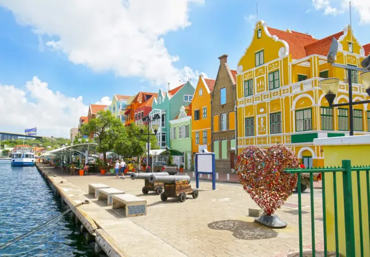 Kolorowe budynki, serce z kłódek i armaty nad wodą – idealne miejsce na curacao wakacje.