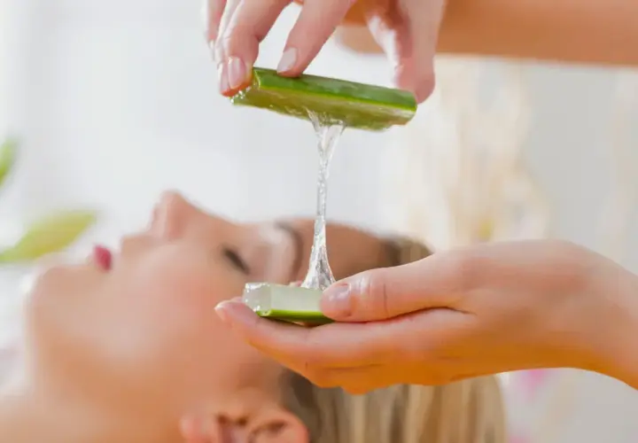 Manos aplican gel de aloe vera en el pelo de una mujer, para un tratamiento de belleza natural.