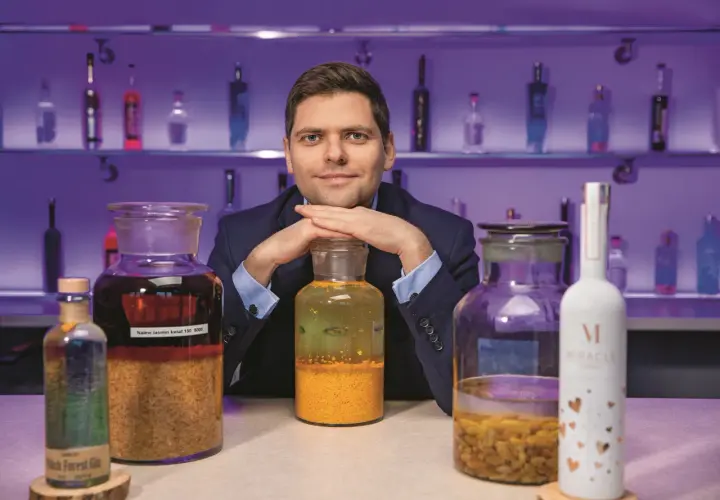 Ekspert prezentuje najlepsze techniki produkcji wódek rzemieślniczych (craft vodka), otoczony butelkami i słoikami z nalewami.