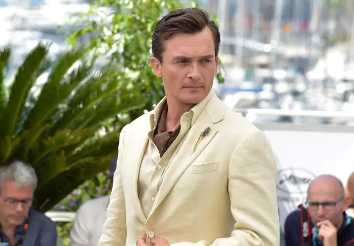 Hombre con un impecable corte de pelo old money, viste un traje de lino color crema y un pañuelo de seda.